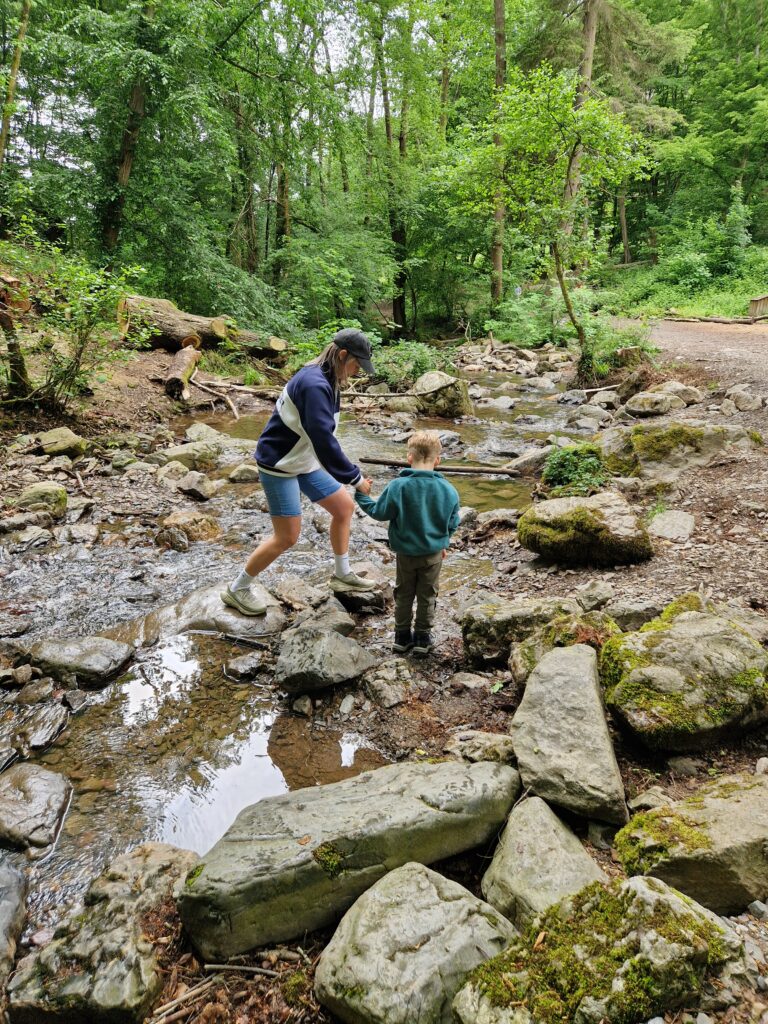 Ninglinspo hike met kinderen - moeder en kind steken rivier over en houden hand vast