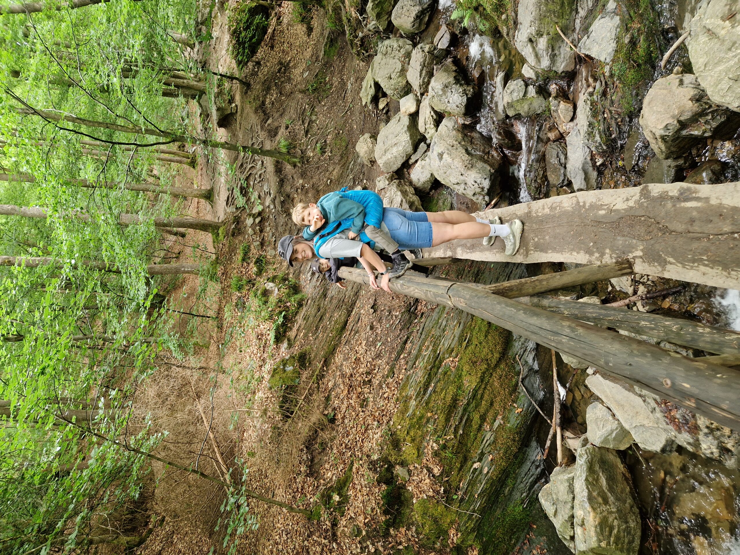 Ninglinspo hike met kinderen - moeder met een kind in een rugzak en een daarnaast op een brug over een riviertje